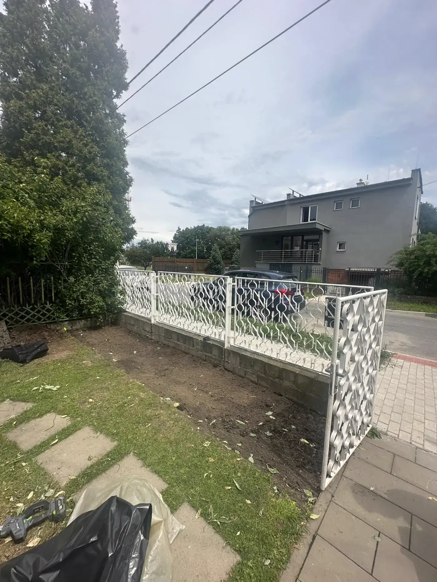 Vyčištěný pruh zeminy podél plotu u chodníku